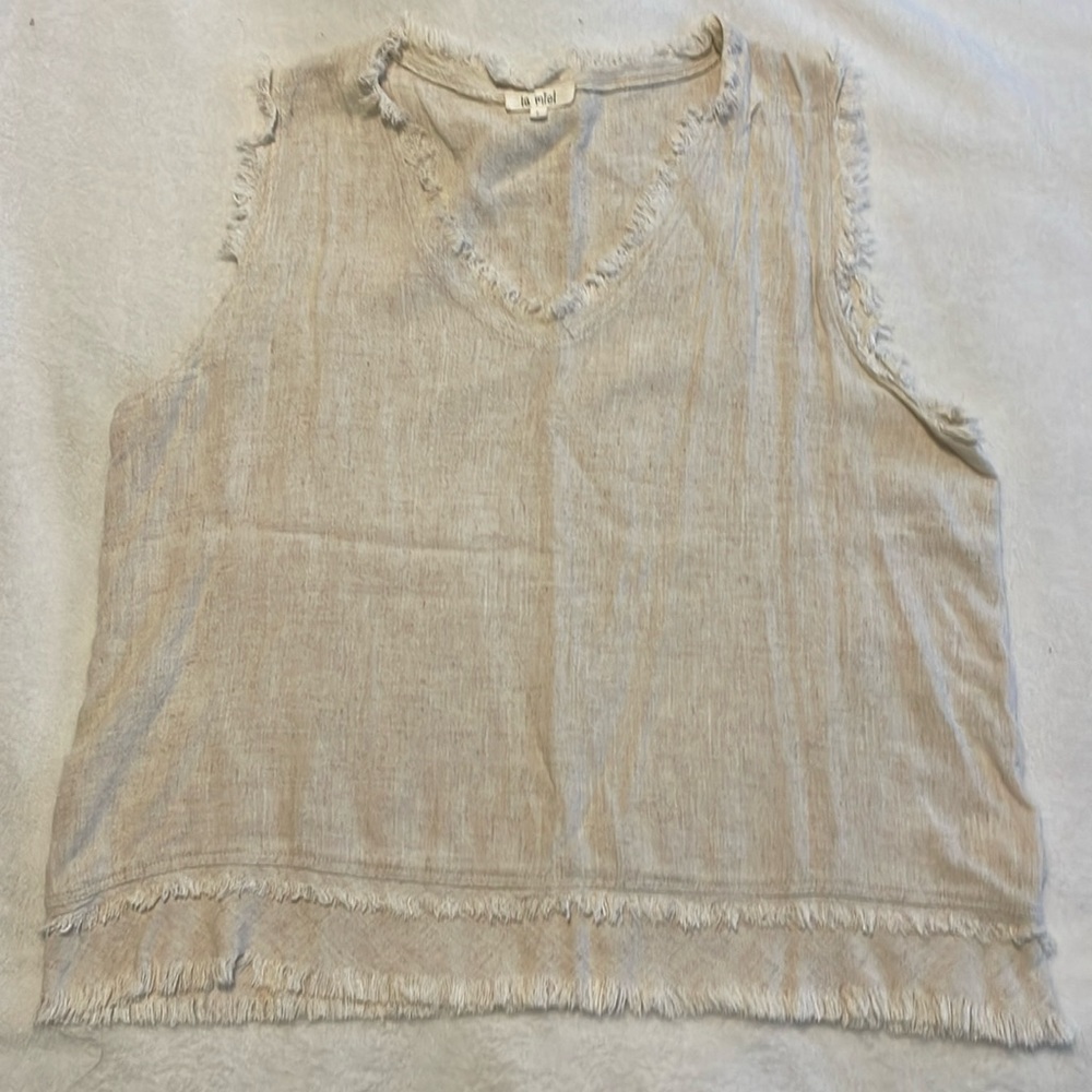 Cream colored sleeveless top with fringe on neckline, sleeves and bottom hem
